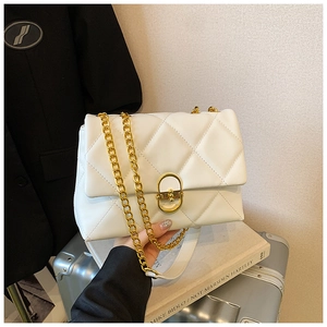Detail of white quilted leather bag with chunky gold chain and circular metal lock closure