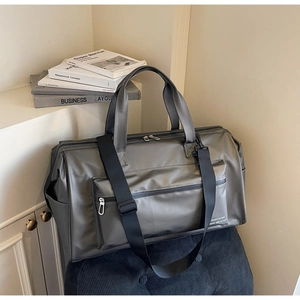 Vue détaillée d'un sac de voyage gris étanche avec poche zippée sur fauteuil en velours