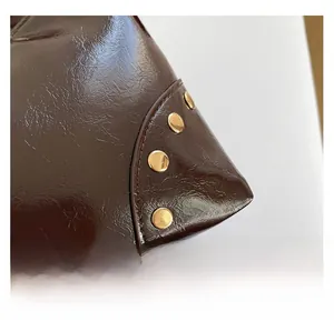 Gros plan détaillé sur le tissu brillant marron foncé avec rivets dorés et coutures de qualité