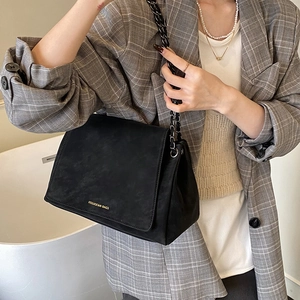 Close-up of black matte suede texture and chain strap on a vintage-style shoulder bag