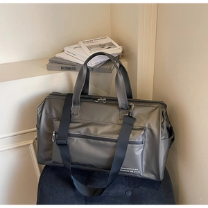 Vue macro du tissu imperméable gris anthracite et de la poignée renforcée du sac de voyage