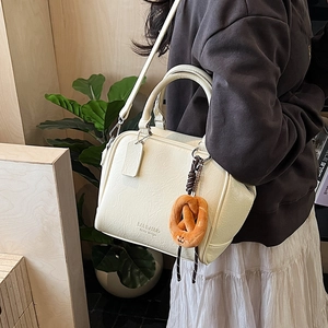 Detail der cremeweißen Retro-Bowlingtasche mit Brezel-Anhänger und Nischen-Design