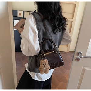Detail view of a vintage dark brown bowling bag with a cute teddy bear plush charm accessory