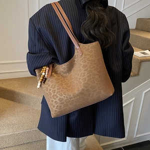 Detail of leopard print tote bag with beaded charm and gold-stamped fashion logo