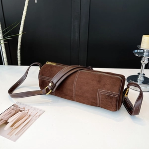 Close-up of brown suede cylinder bag with white contrast stitching and gold hardware