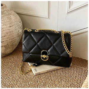 Detail of black quilted leather shoulder bag with gold chain strap and metallic clasp