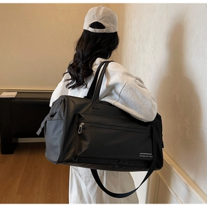 Vue arrière d'un sac de voyage noir imperméable en nylon avec bandoulière dans un salon