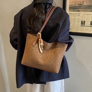 Detail of leopard print tote bag with beaded charm and vintage textures