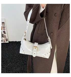 Détail du sac porté épaule en cuir verni blanc avec boucle dorée et rivets métalliques