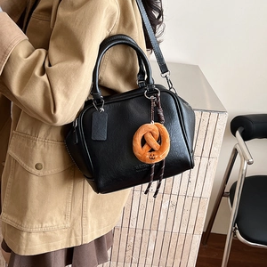 Detailansicht einer schwarzen Leder-Bowlingtasche mit orangefarbenem Plüsch-Anhänger