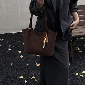 Detail of leopard print embossed tote bag with colorful wooden beads on autumn background