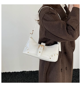 Détail du sac à bandoulière blanc punk avec boucles dorées et rivets sur le cuir