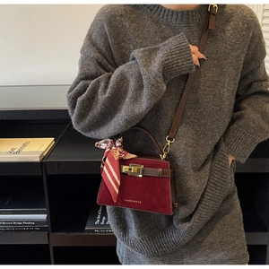 Detail showing burgundy matte suede square bag with silk scarf and gold lock clasp