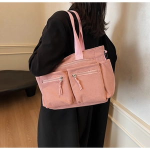 Sac fourre-tout rose en velours côtelé avec deux poches zippées porté par un mannequin