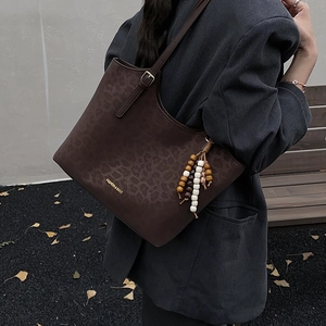 Detail of leopard print tote bag with wooden bead tassel and fashion logo in autumn setting