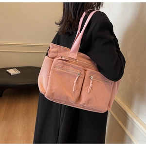 Détail du sac cabas en velours côtelé rose avec deux poches zippées devant et bandoulière