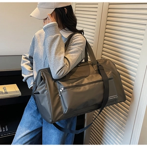 Vue détaillée du grand sac de voyage gris-vert porté par un mannequin réel