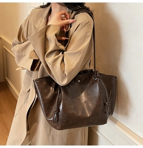 Detail view of brown faux leather tote bag with drawstring knot and oil-wax texture