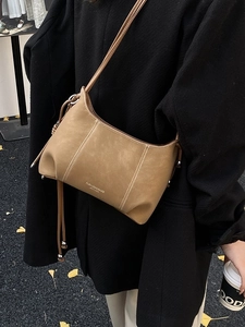 Brown vintage leather crossbody bag with white stitching shown on a model