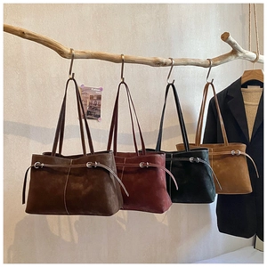 Detail of four colorful suede tote bags hanging on a wooden branch for display