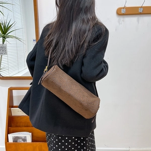 Detail of leopard print cylinder underarm bag with sleek dark brown strap and gold buckle