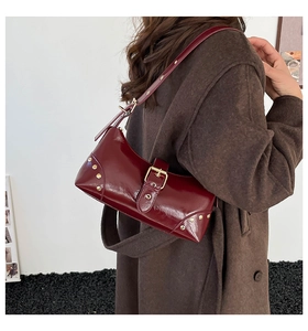 Détail du sac à bandoulière en cuir verni bordeaux avec rivets dorés et boucle