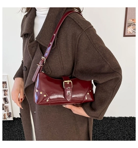 Détail du sac à bandoulière en cuir verni bordeaux avec rivets dorés et boucle
