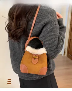 Dettaglio borsa a secchiello in pelle scamosciata marrone con bordo in peluche e chiusura d'oro