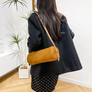 Detail of brown cylinder bag showing animal print texture and golden hardware buckle