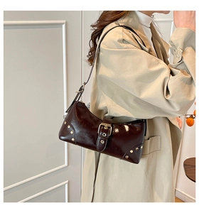 Détail du sac à bandoulière en cuir marron avec rivets métalliques et boucle ajustable