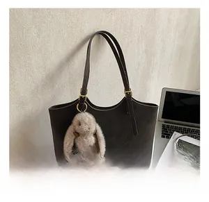 Detail of dark brown matte leather tote bag with elegant gold hardware and plush charm