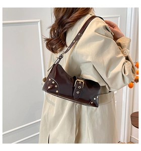 Vue de profil du sac à bandoulière en cuir verni marron foncé avec rivets et boucles dorés