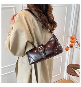 Détail du sac porté épaule en cuir verni marron avec boucles vintage et rivets en métal