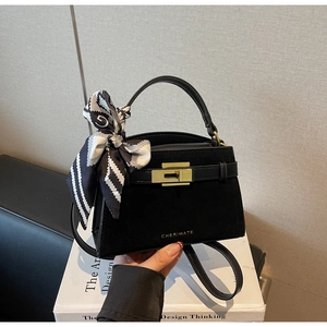 Detail of black suede and leather handbag featuring gold lock and patterned silk scarf