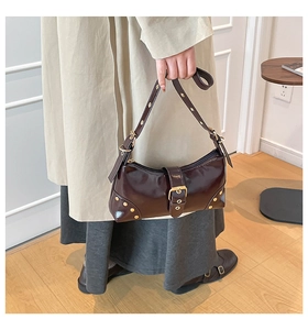 Détail du sac porté épaule en cuir verni marron avec boucles dorées et rivets stylés