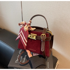 Close-up of burgundy velvet handbag with leather trim, twist-lock, and decorative scarf