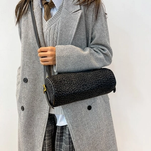 Macro detail of black cylindrical crossbody bag featuring matte leopard texture and hardware
