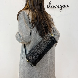Close-up of leopard print cylinder bag with gold hardware on long coat model