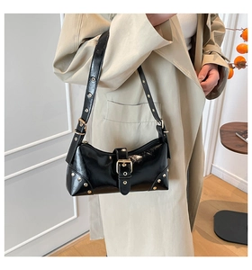Détail d'un sac d'épaule en cuir verni noir brillant avec rivets dorés et œillets métalliques