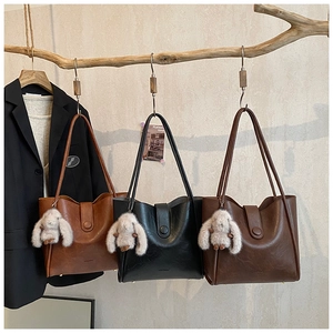 Three leather tote bags in caramel, black, and dark brown with rabbit charms on branches