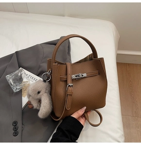 Dettaglio borsa a secchiello in pelle marrone con chiusura argento e ciondolo a coniglio