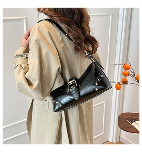 Détail du sac à épaule punk noir avec rivets et finition en cuir verni brillant