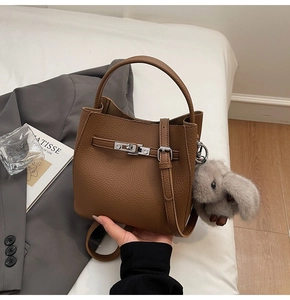 Dettaglio borsa a secchiello in pelle litchi marrone con chiusura argento e charm a coniglio