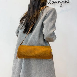 Leopard print cylinder shoulder bag in mustard suede shown with a long grey winter coat