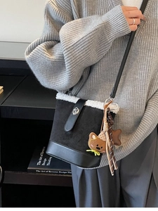 Bolso vintage tipo cubo negro con ribete de lana blanca y colgantes sobre una modelo