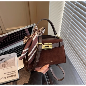 Detail of suede textured square bag with golden lock and striped silk scarf wrap