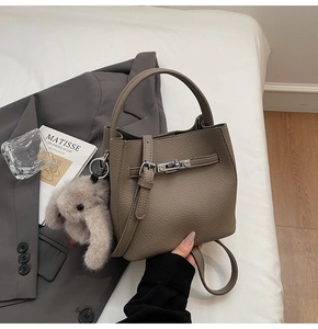 Dettaglio borsa a secchiello taupe in pelle martellata con ciondolo a coniglio e tracolla