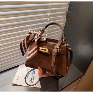 Detail of brown suede crossbody bag with silk scarf handle and metal turn-lock closure
