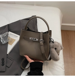 Dettaglio borsa a secchiello in pelle taupe con chiusura argento e ciondolo koala morbido