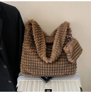 Brown faux fur tote bag with textured grid pattern placed on a white suitcase